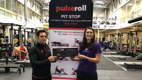 two people standing in the gym in front of a Pulseroll banner